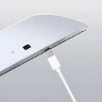 Close-up of a white USB cable plugging into a sleek silver metallic electronic device.