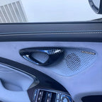 Premium carbon fiber texture tweeter cover on a grey leather car door panel with Dynaudio speaker.