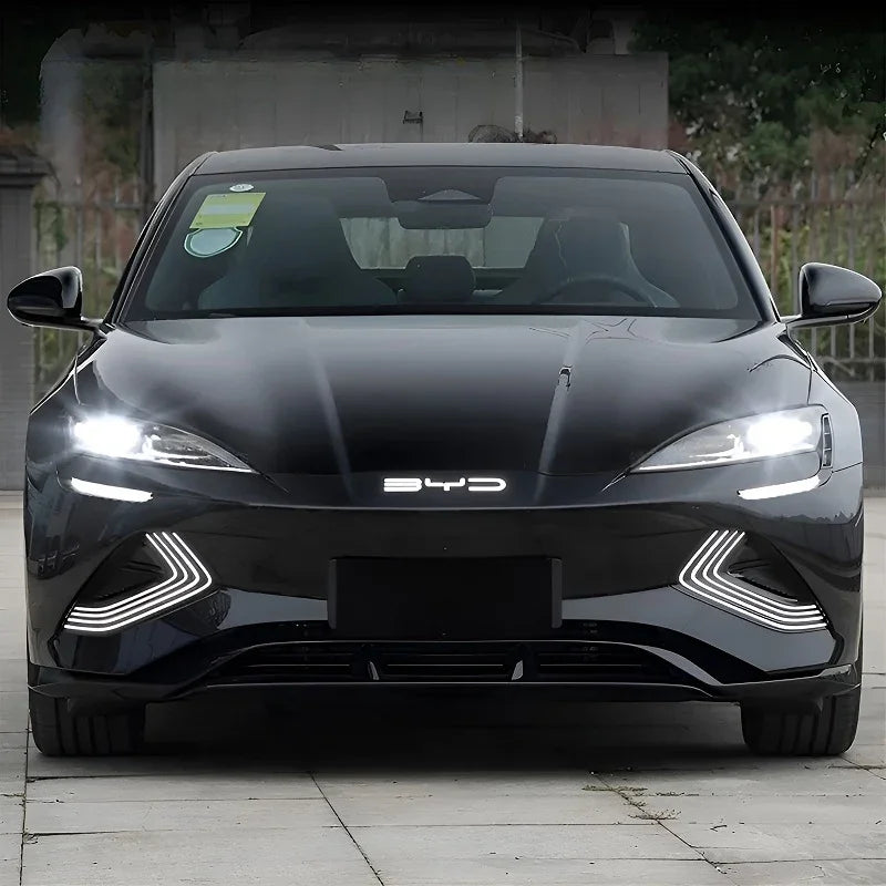 Front view of a sleek black BYD electric sedan featuring bright LED headlights and a glossy finish.