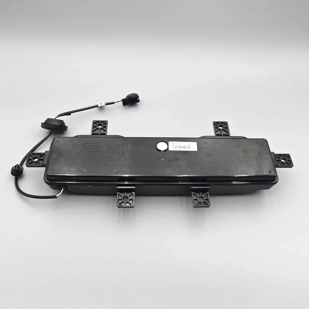 Black durable plastic trunk liner component with integrated wiring and connector.