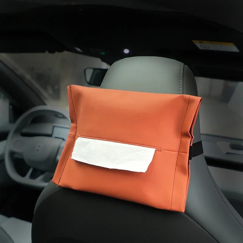 Orange leather car seat organizer with a white tissue pocket attached to a grey car seat headrest.