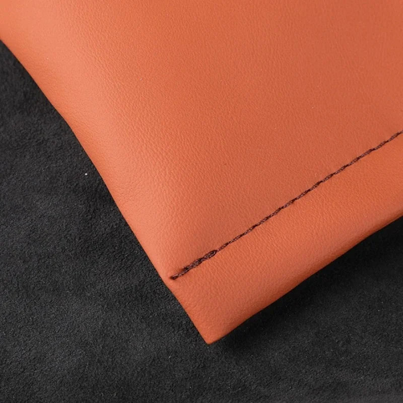 Close-up of premium brown synthetic leather material with precise black stitching.
