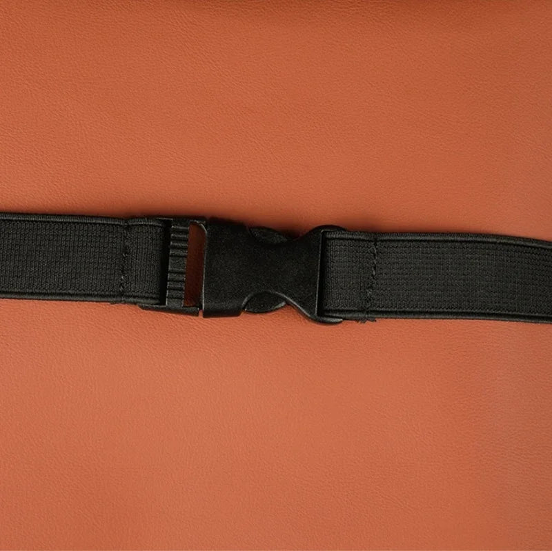 Close-up of a black nylon strap with a plastic buckle on a brown leather surface.
