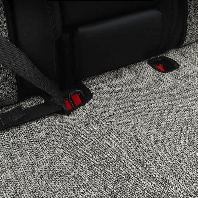 Close-up of grey textured fabric car mats with secure black straps and red locking clips.