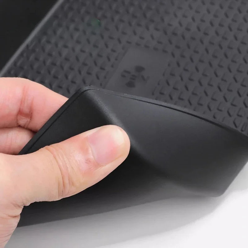 Close-up of a flexible, black textured rubber car floor mat showing its durable material.