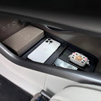 Black textured organizer tray in a car console holding a white smartphone and accessories.