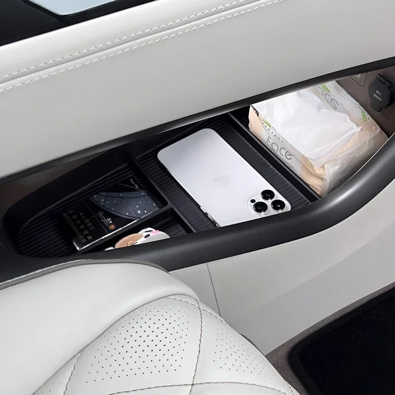 Black organizer tray in a white car center console holding a smartphone and facial tissues.