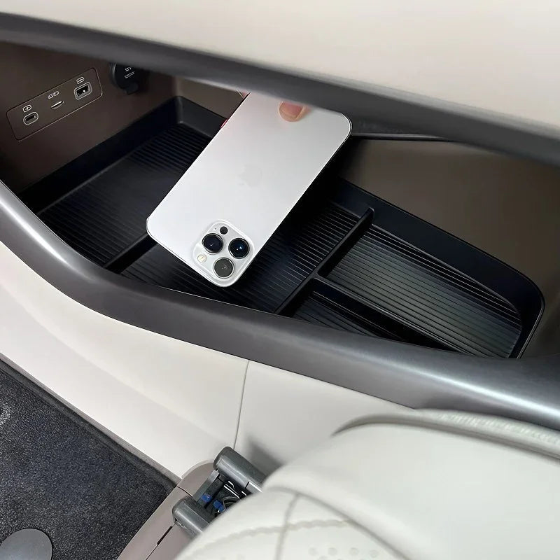 Black ribbed silicone organizer tray in a car console holding a white smartphone.