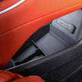 Black textured plastic car organizer tray installed in an orange leather interior with USB ports.