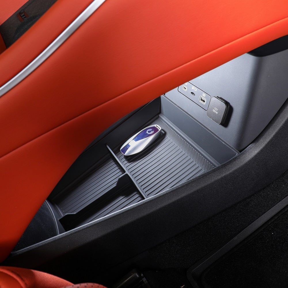 Black textured car seat storage compartment featuring a sleek silver electronic device.