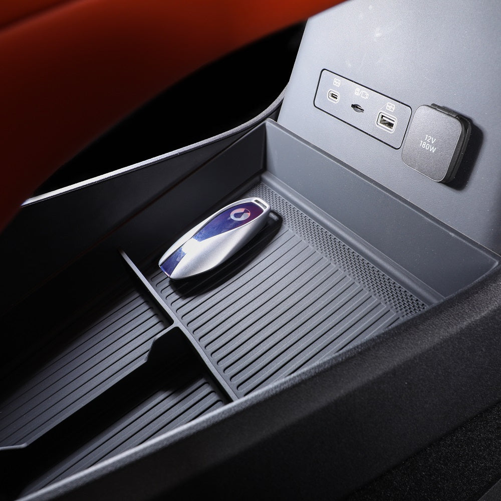 Black textured rubber center console organizer tray with a car key fob inside.