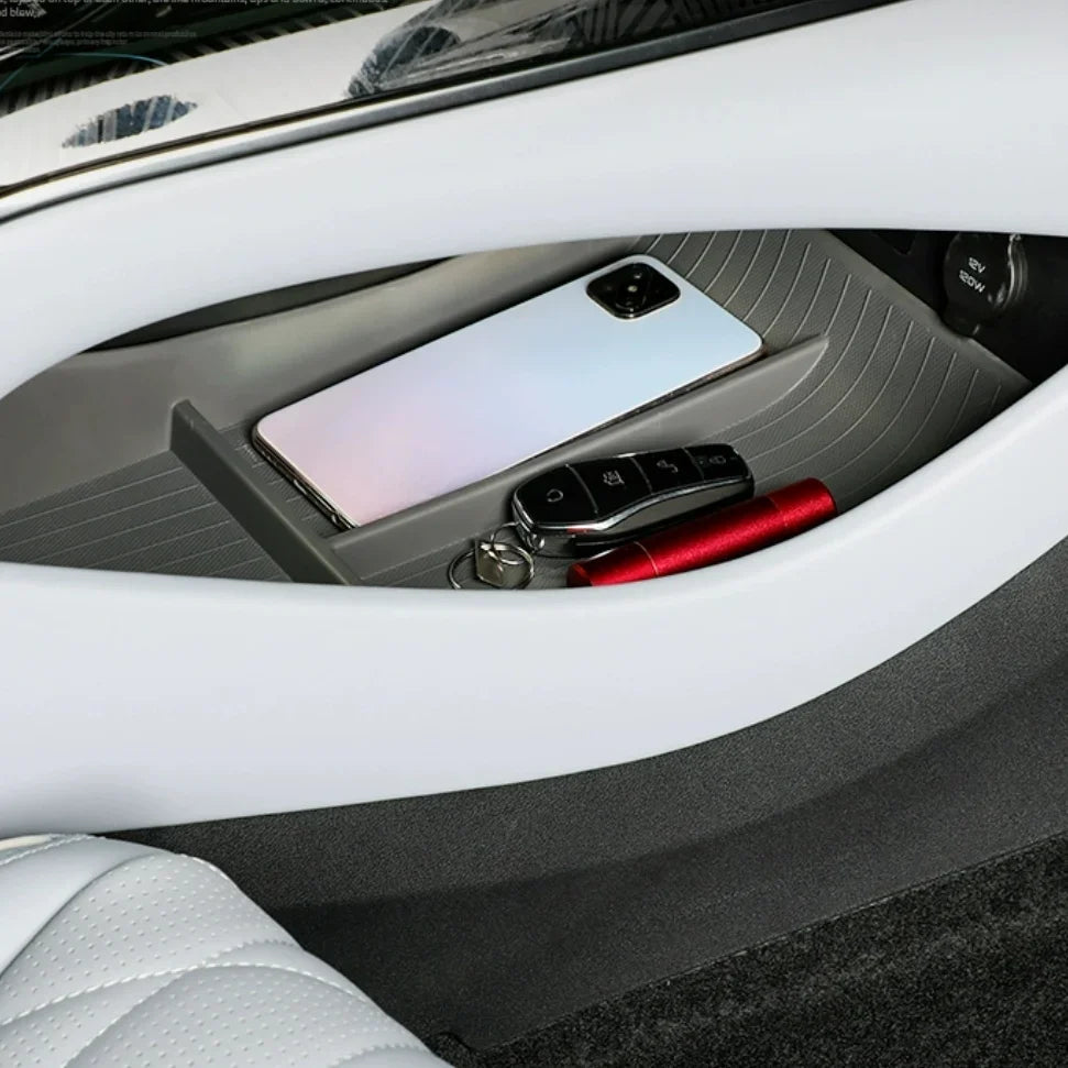 Grey textured car console organizer tray holding a smartphone, key fob, and red pen.