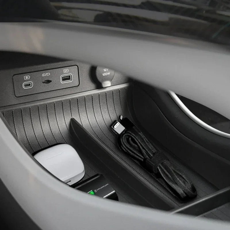 Black textured anti-slip storage tray with USB ports and 12V power outlet in car console.