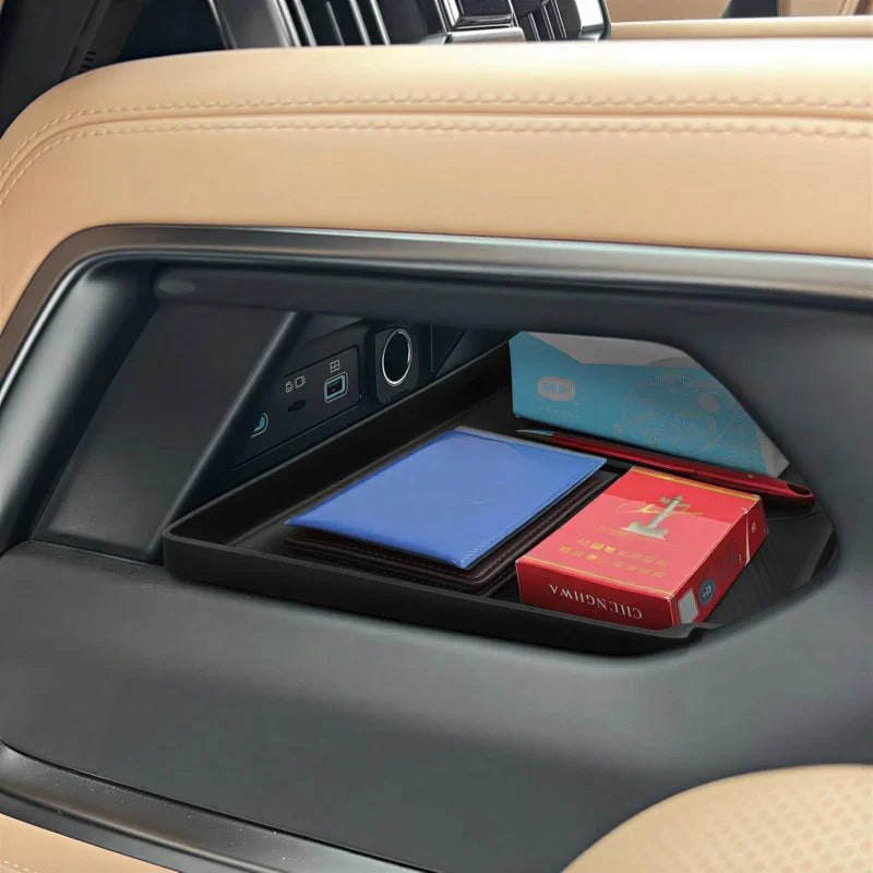 Black custom-fit door pocket organizer tray holding a blue wallet and red box in a car interior.