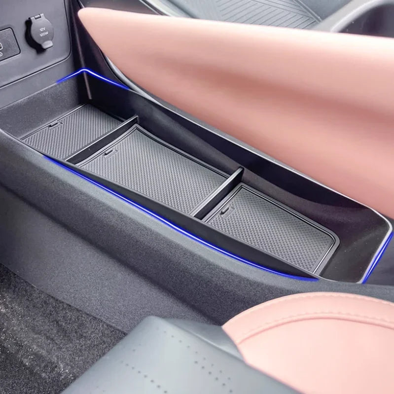 Black textured car door storage tray with blue ambient lighting and pink leather interior.
