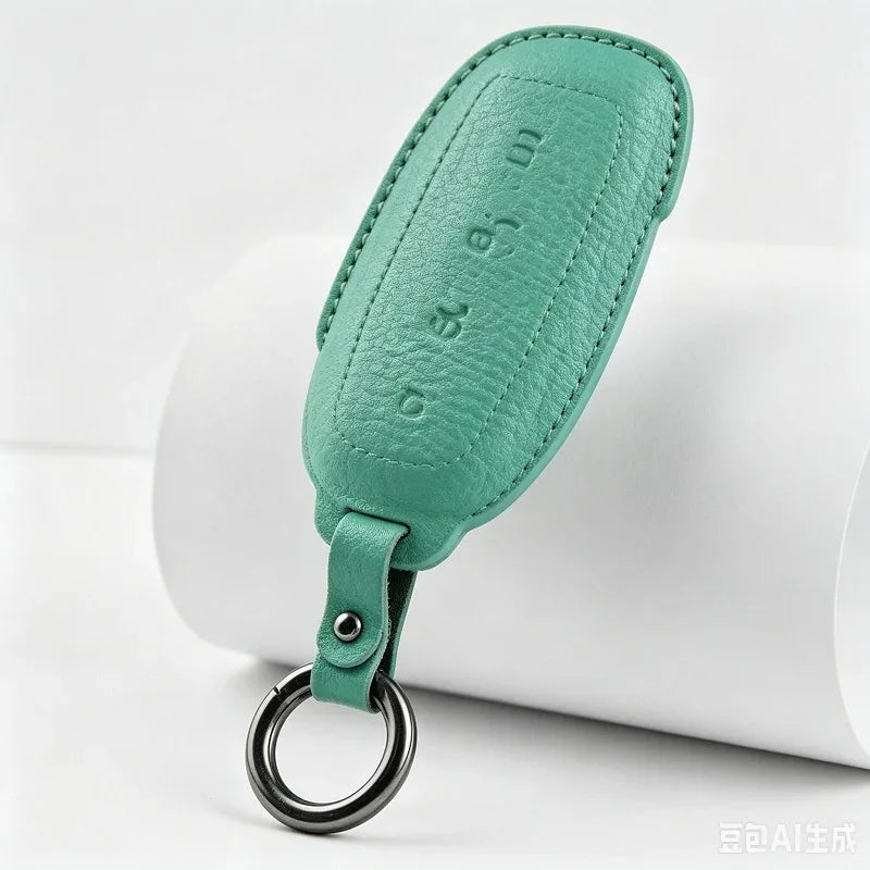 Premium teal green textured leather key fob with embossed lettering and silver metal ring.