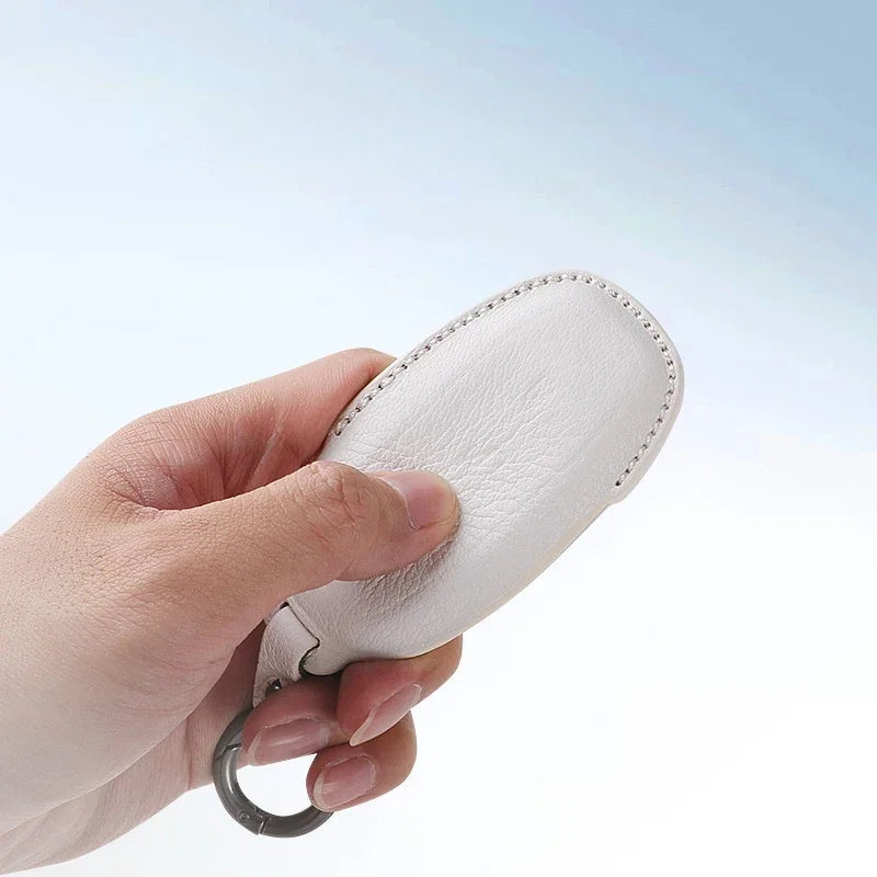 Hand holding a professional white leather car key case with precision stitching.