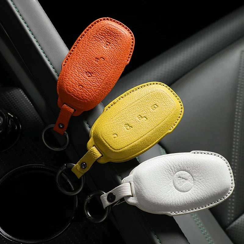 Premium textured leather car key covers in orange, yellow, and white for BYD protection.