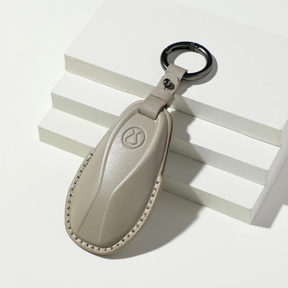 Tan leather BYD car key fob with embossed logo and silver ring on white blocks