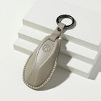 Tan leather BYD car key fob with embossed logo and silver ring on white blocks
