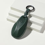 Premium dark green leather car key fob cover with elegant textured finish and metal ring.