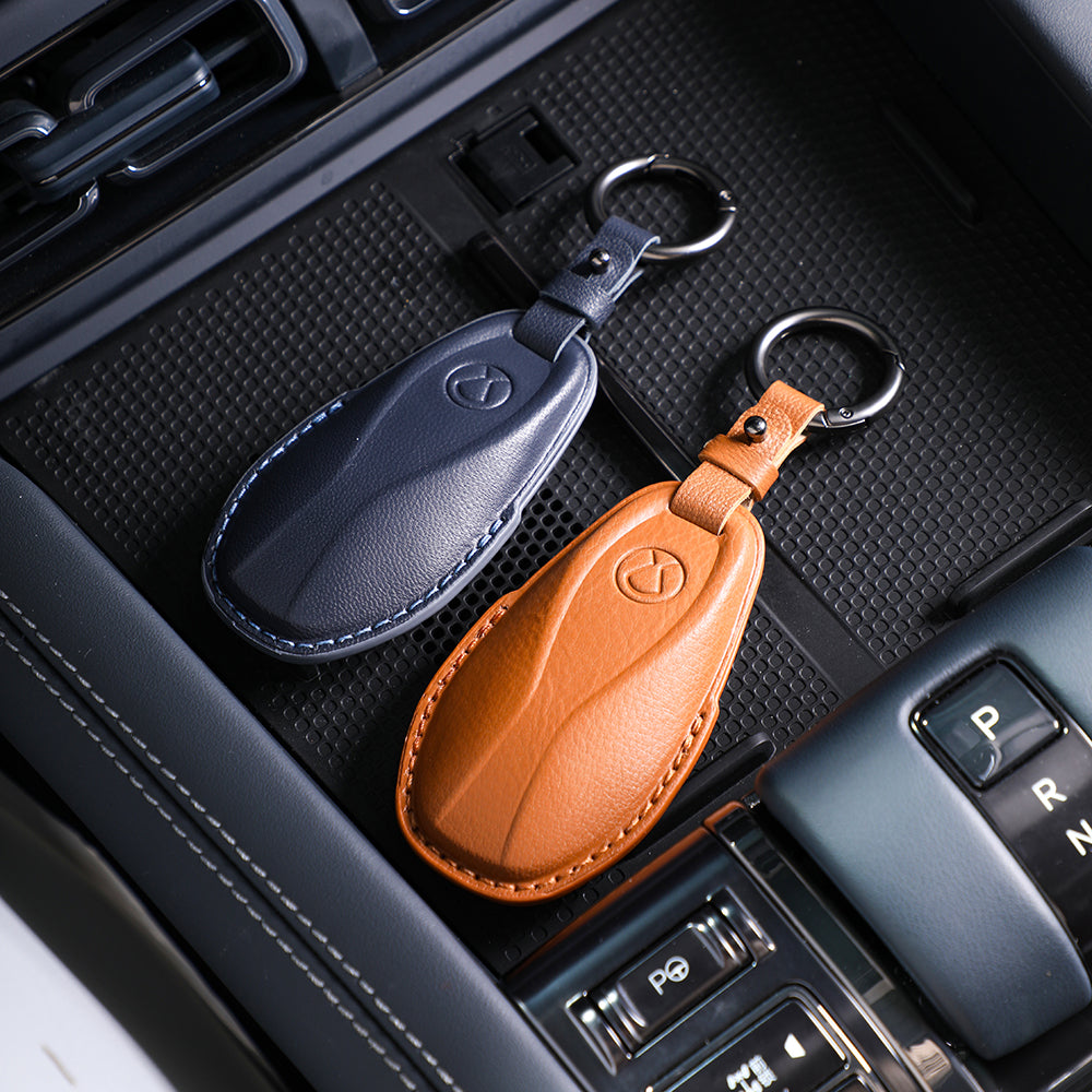 Premium leather car key fob covers in navy blue and tan brown with elegant stitching.