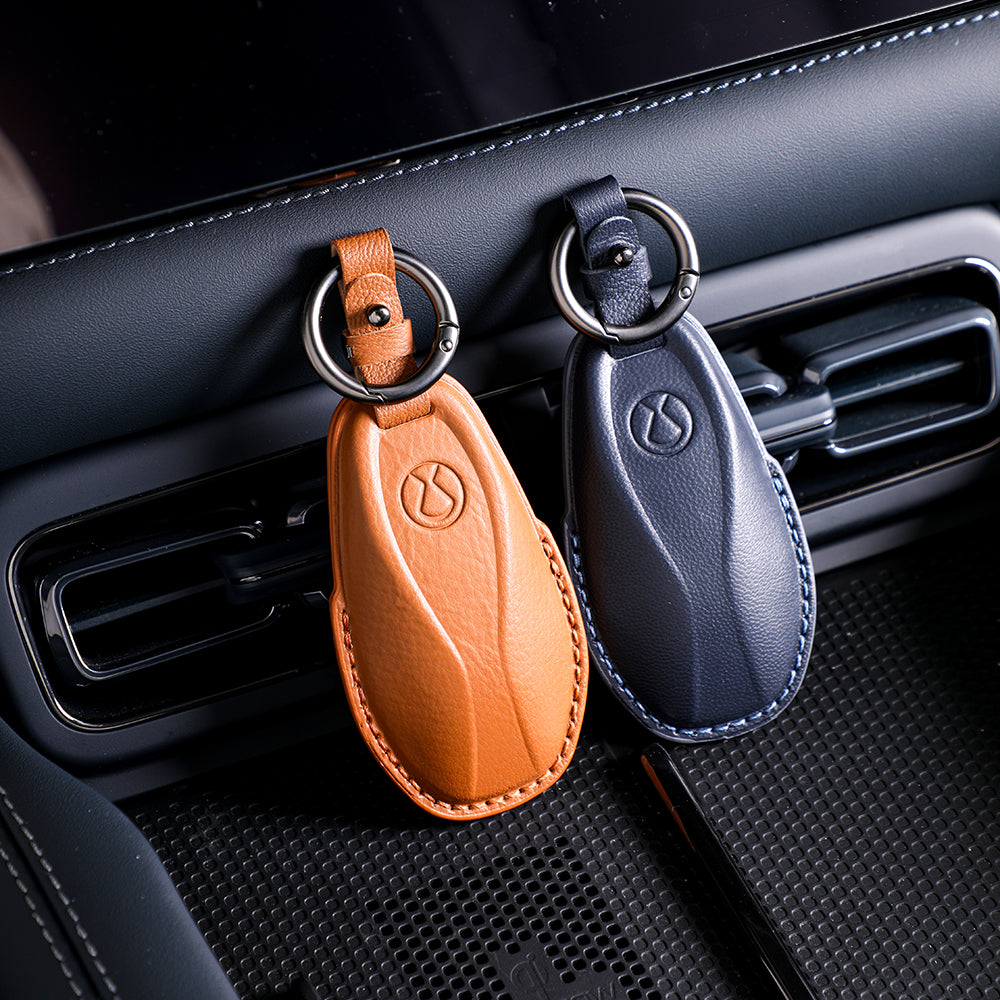 Premium leather car key fob covers in tan and navy blue with elegant stitching.