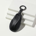 Premium black textured leather car key fob cover with protective stitching.