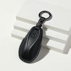 Premium black textured leather car key fob cover with protective stitching.