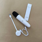 White wireless handheld microphone with a compact charging receiver and USB cable.