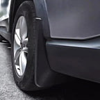 Close-up of a durable matte black plastic mud guard installed behind a car tire.