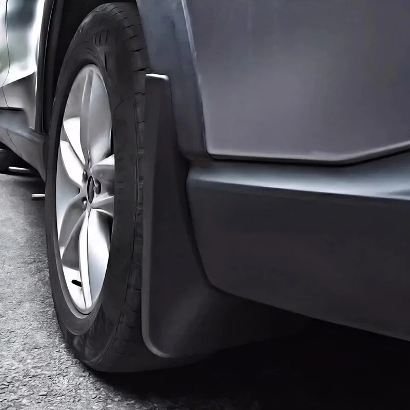 Close-up of a durable matte black plastic mud guard installed behind a car tire.