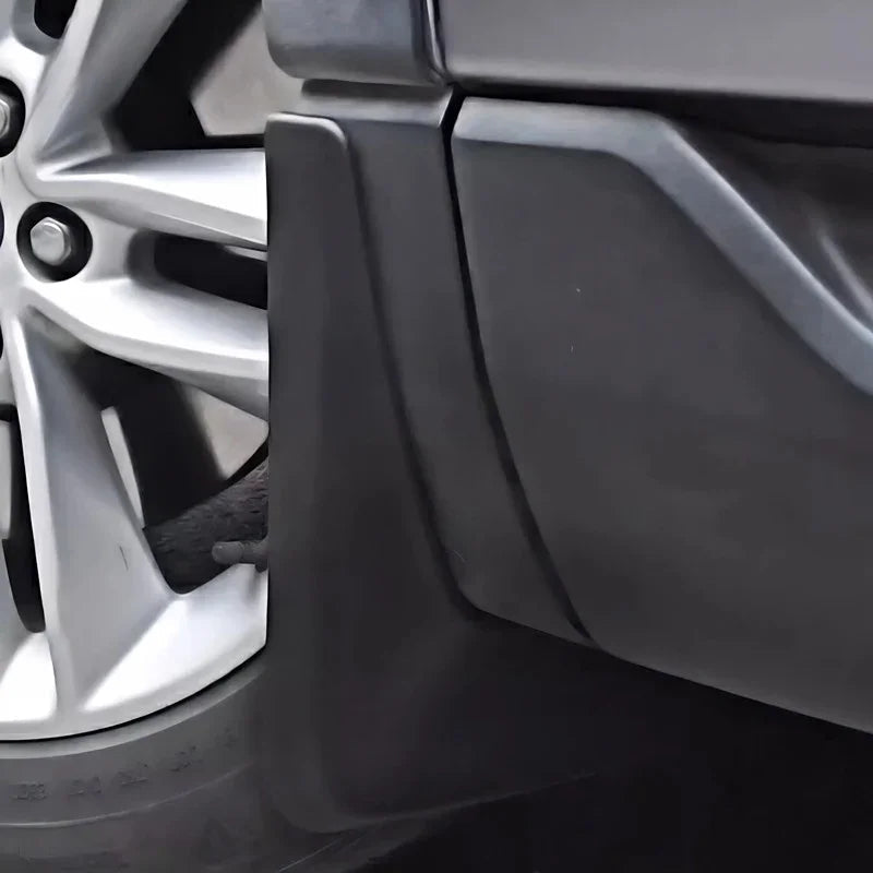 Close-up of a matte black durable plastic mudguard installed on a vehicle wheel arch.