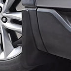 Close-up of a matte black durable plastic mudguard installed on a vehicle wheel arch.
