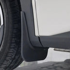 Close-up of a durable matte black plastic mud guard installed on a white vehicle.