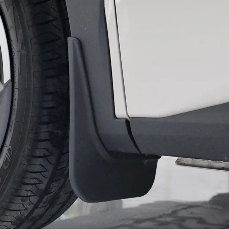 Close-up of a durable matte black plastic mud guard installed on a white vehicle.
