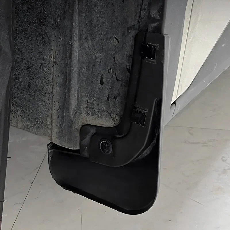 Close-up of a durable black plastic car mud guard installed on a vehicle chassis.