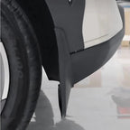 Close-up of a durable matte black plastic mud guard installed on a white vehicle wheel arch.
