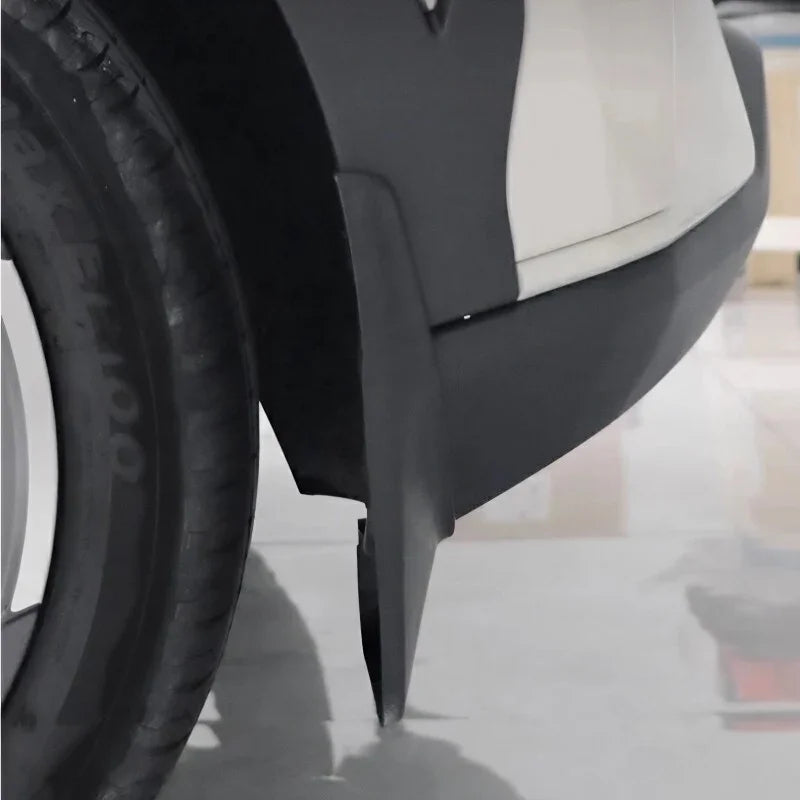 Close-up of a durable matte black plastic mud guard installed on a white vehicle wheel arch.