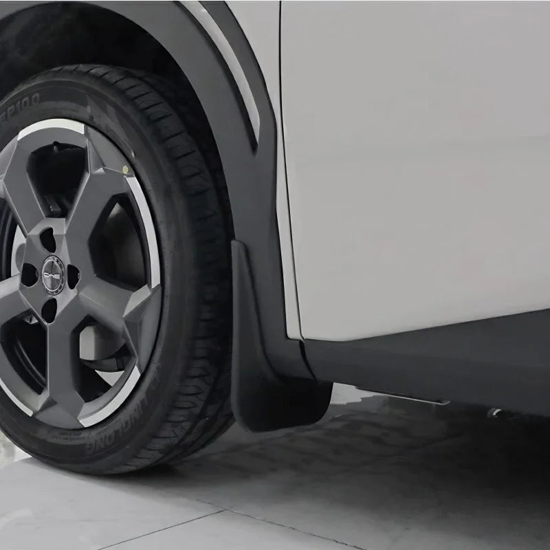 Close-up of a durable matte black plastic mud guard installed behind a car wheel.