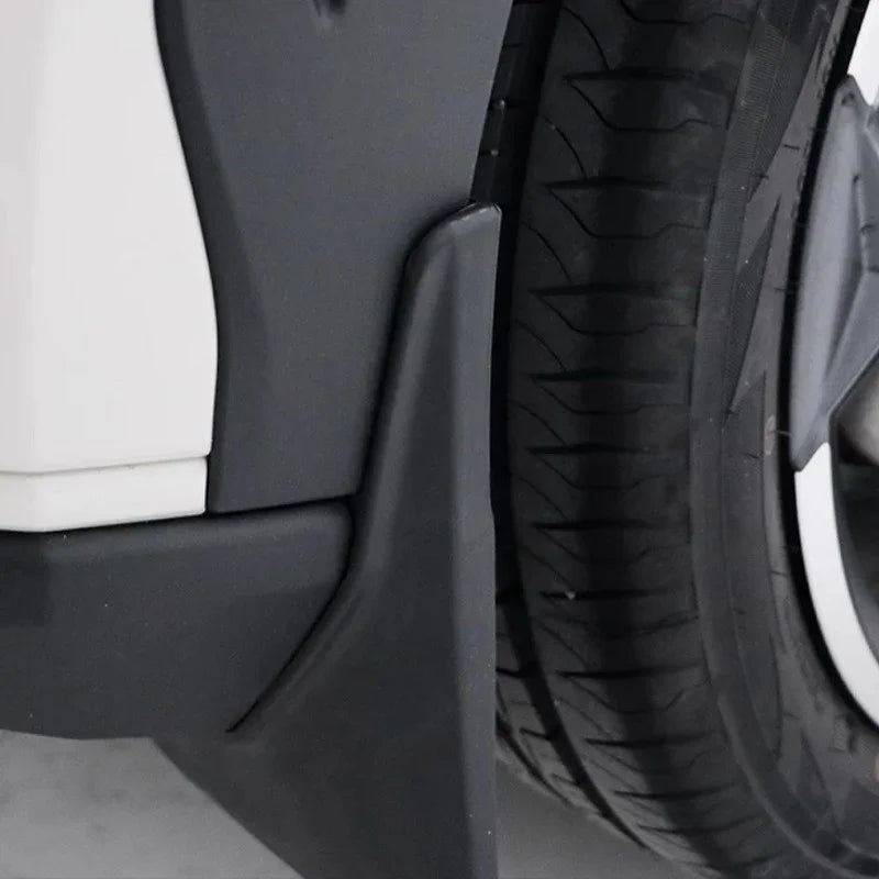 Close-up of a durable matte black plastic mudguard installed behind a car tire.