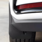 Durable matte black plastic mud flap installed on the rear bumper for vehicle protection.
