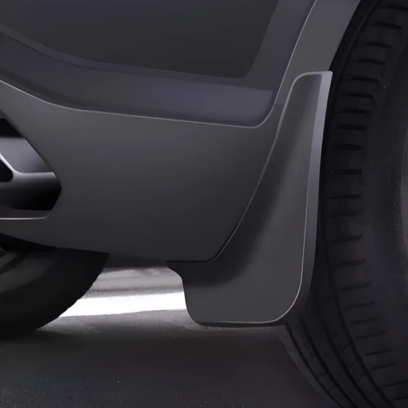 Matte black durable plastic mud flap installed behind the front wheel for vehicle protection.