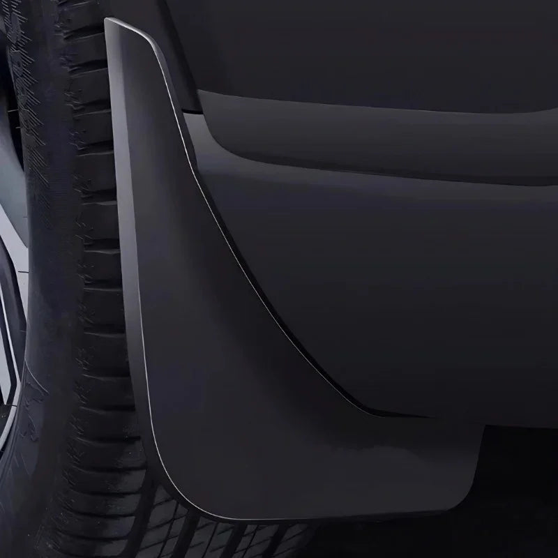 Close-up of a durable matte black plastic mud guard installed behind a car tire.