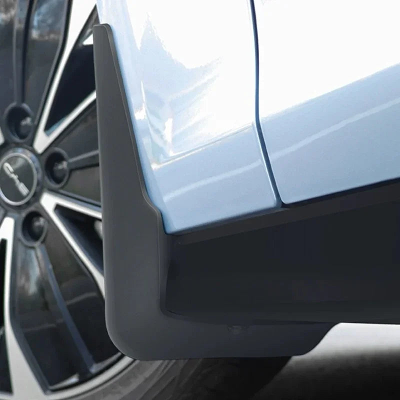 Matte black durable rubber mud flap installed on a light blue car fender for splash protection.