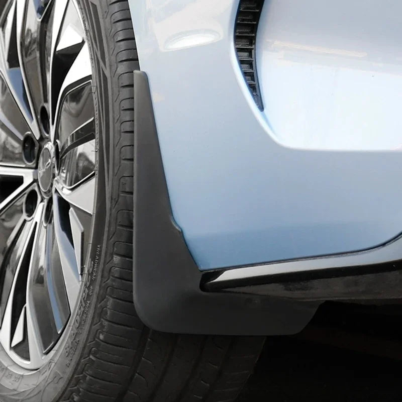 Black matte durable rubber mud flap installed on a light blue car wheel arch for protection.