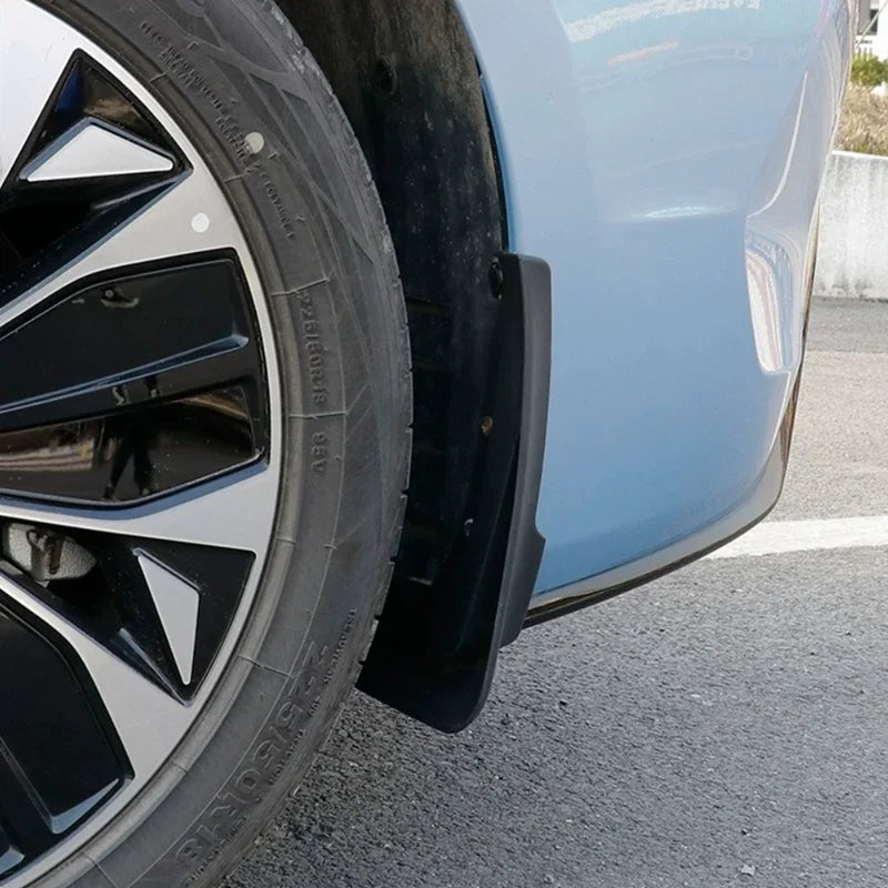 Black durable rubber mud flap installed on a light blue car wheel arch for protection.