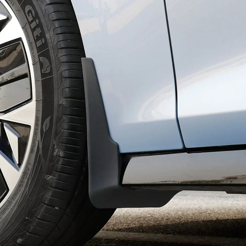 Matte grey durable plastic mud flap installed on a light blue car wheel arch for protection.