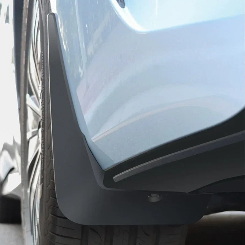 Durable matte black rubber mud flap installed on a light blue car to protect against road debris.