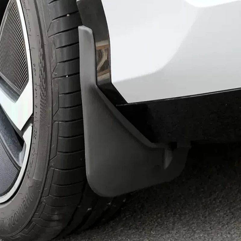 Close-up of a durable matte black plastic mud guard installed behind a car wheel.